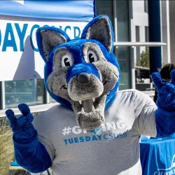 Cody Coyote at a Giving Tuesday sign.