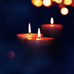 three lit candles in the dark