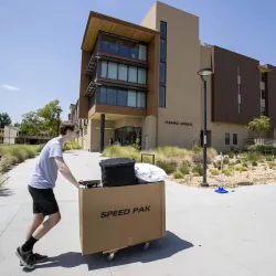 A student pushes a cart of his belongings as he makes his way to his on-campus home during Move-In days.