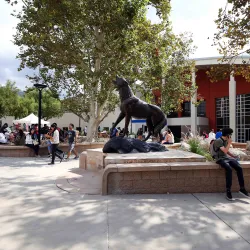 Photo of students on campus, at the Wild Song stature