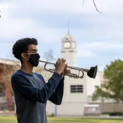 CSUSB student William Parada plays his trumpet outside. Through a series of approved hybrid classes and safety precautions, the music lives on. 
