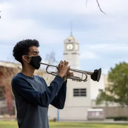 CSUSB student William Parada plays his trumpet outside. Through a series of approved hybrid classes and safety precautions, the music lives on.