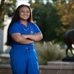 Nursing student standing by the Wild Song statue at CSUSB