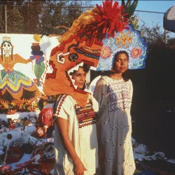 : Photograph of Ofelia Esparza and her daughter, Rosanna Esparza-Ahrens, wearing paper mache constructions worn as helmets with large geometric designs, 1980.