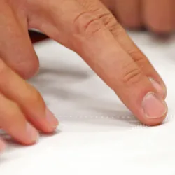 Fingers trace Braille on a page.