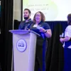 Members of the Human Resources team presenting their process improvement project at the Process Improvement & Lean Operations (PILOT) Year-End Showcase, with one presenter speaking at a podium while team members stand alongside.
