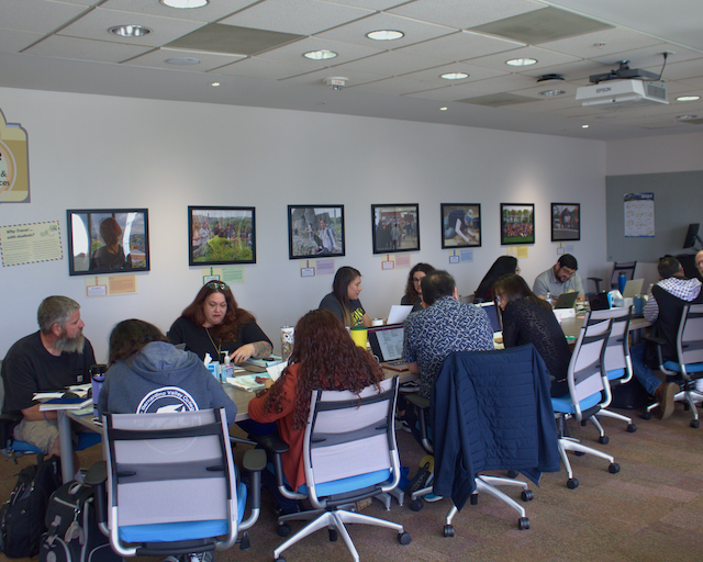 A group of individuals seated at tables, engaged in conversation.