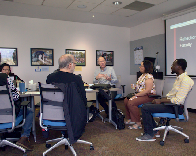 ​​A group of individuals seated on chairs in a room.