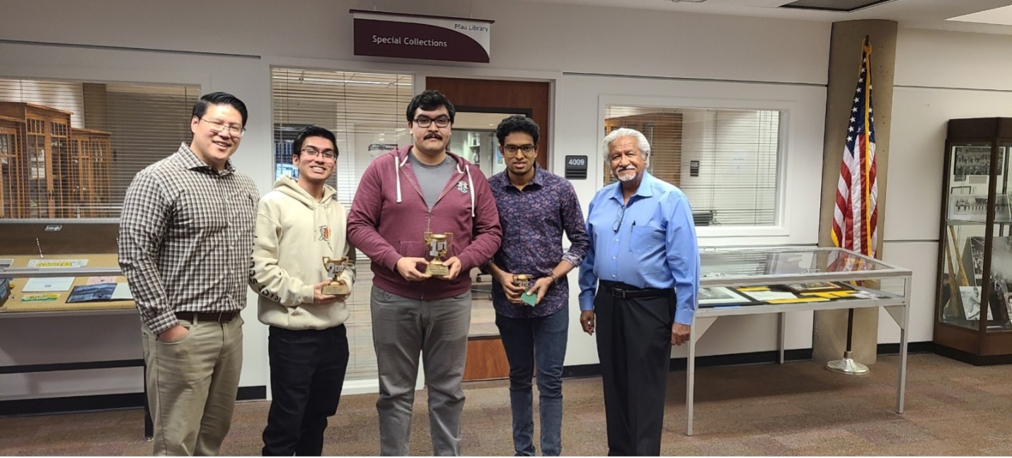Chris Han (past-president of the Chess Club and current member of the newly formed Chess Kings (support group) is standing to the left of the winners. Cesar Caballero, dean emeritus of the Pfau Library is standing to the right of the group. He is the current lead for chess activities on campus