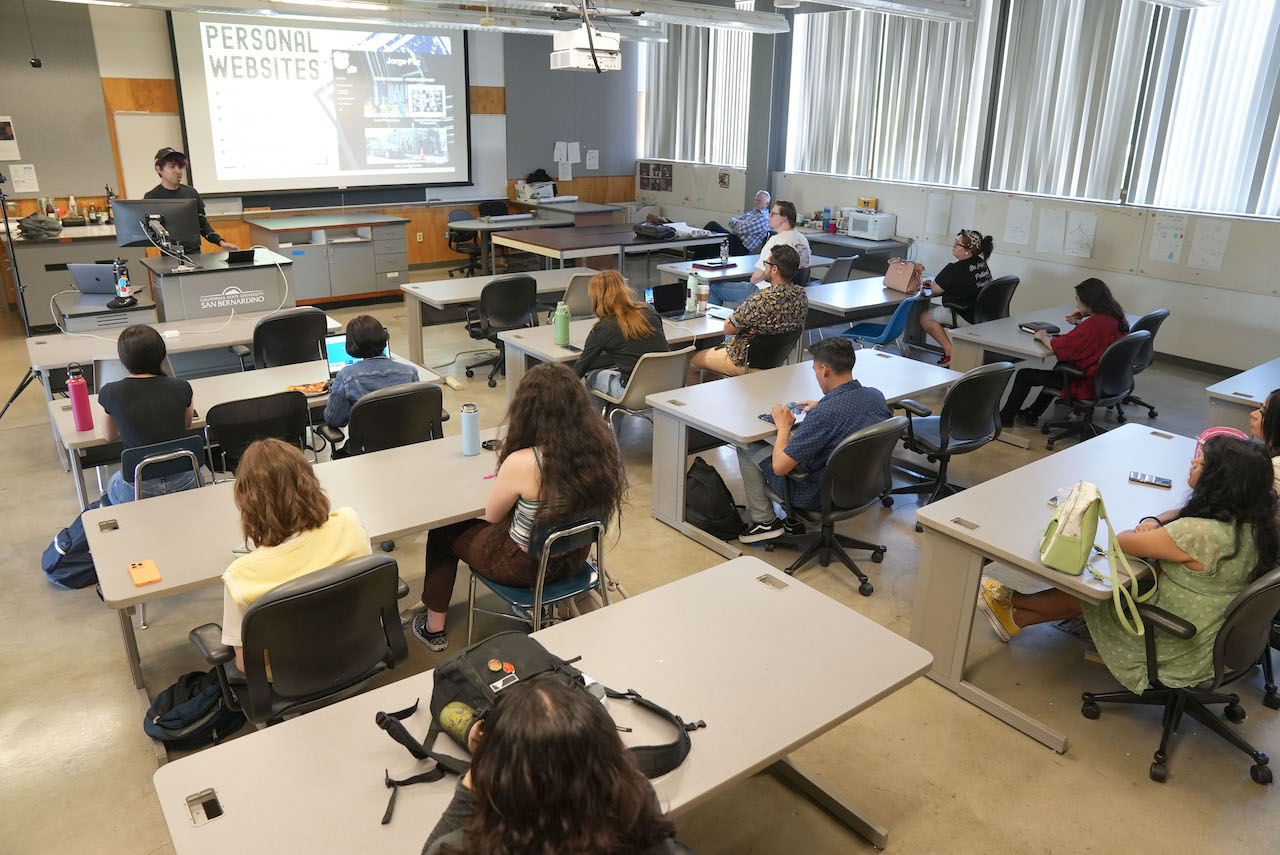 A classroom with students at desks and a mentor standing in front, teaching.