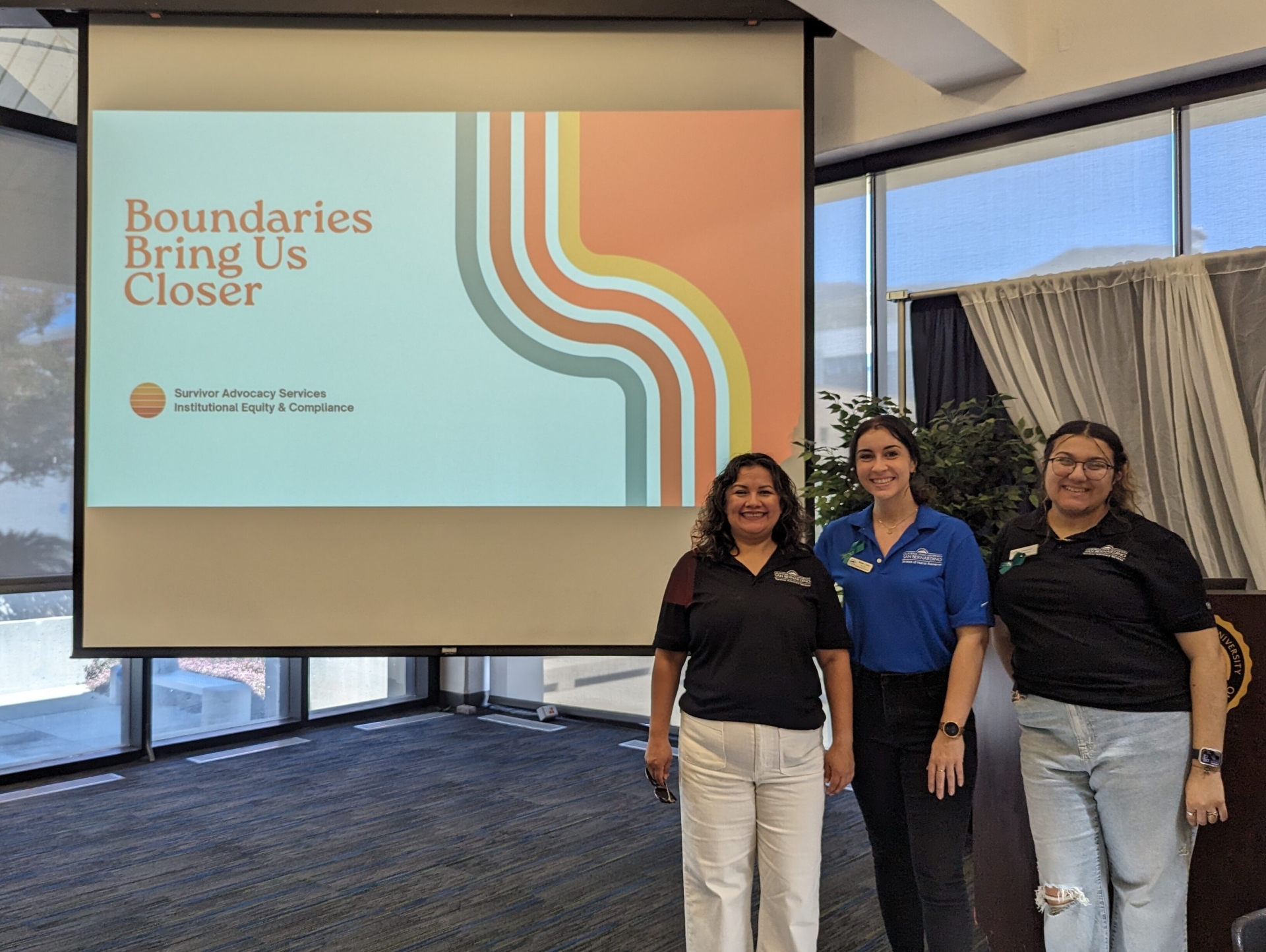 Three CSUSB staff stand in front of screen that reads "Boundaries Bring us Closer"