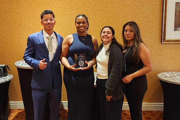 The JHBC undergraduate team, left to right, Juan Sibrian, Lauren Hunter (with award), Irene Barajas and Princesa Villegas.