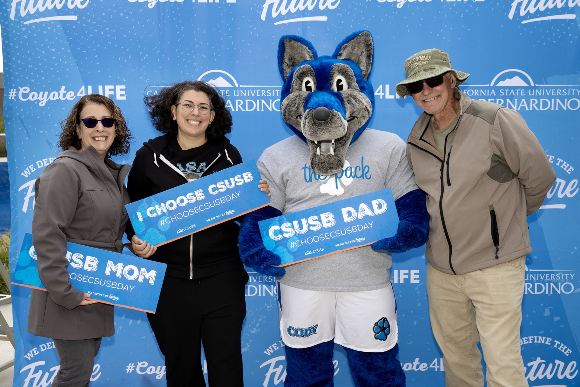 ​​​​A family poses with Cody Coyote on Choose CSUSB Day.