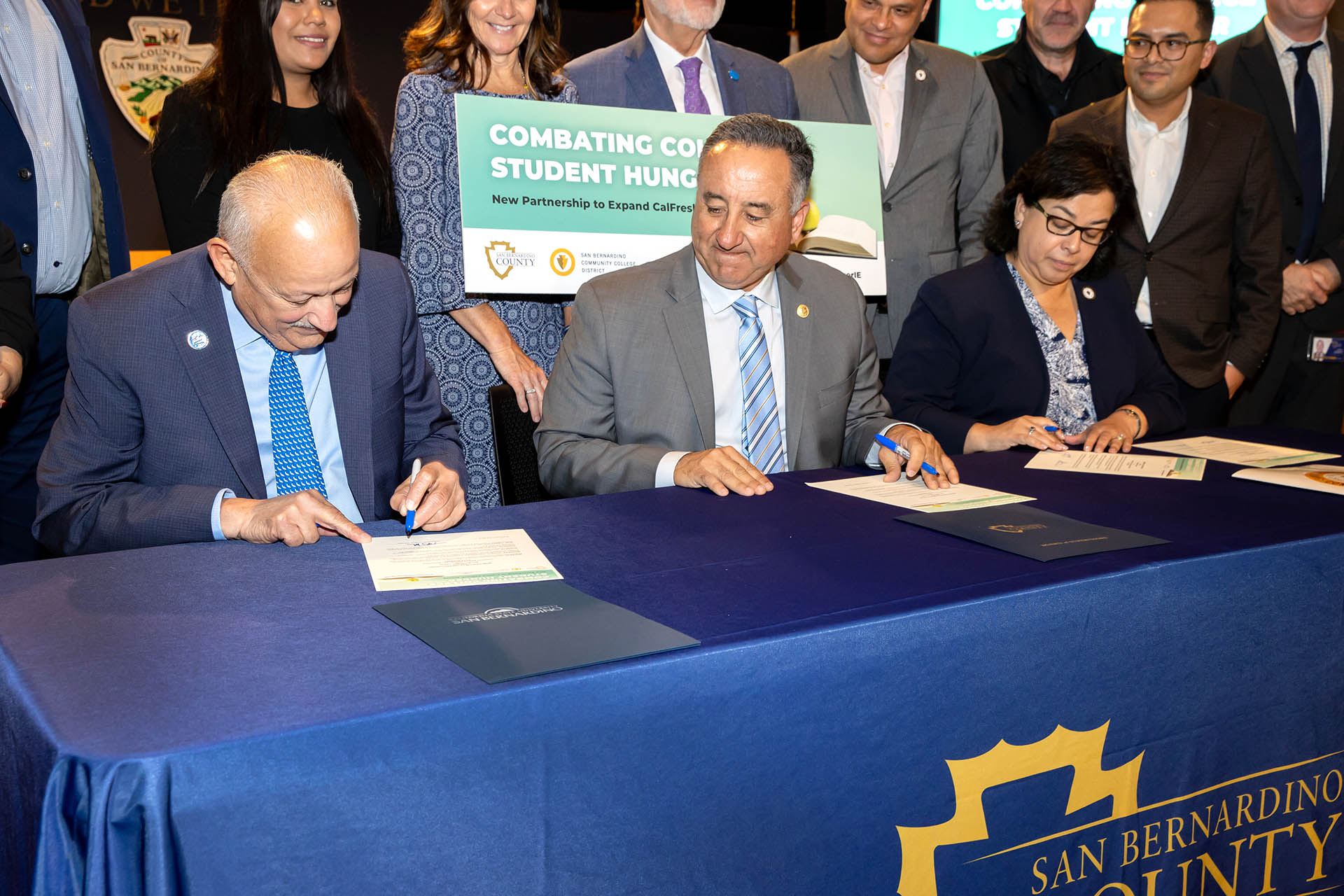 CSUSB President Tomás D. Morales (left) signs the memorandum of understanding that will increase the accessibility of California’s CalFresh Program, the state’s name for the federal Supplemental Nutrition Assistance Program, or “SNAP.” Looking on ar San Bernardino County 5th District Supervisor Joe Baca Jr., and San Bernardino Community College District Chancellor Diana Z. Rodriguez.
