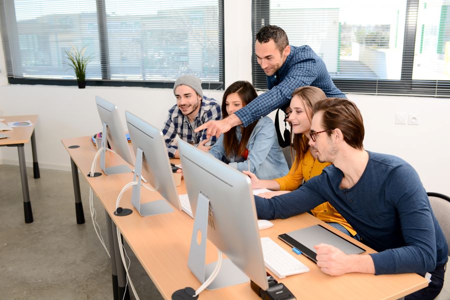 Male teacher assisting a group of students.