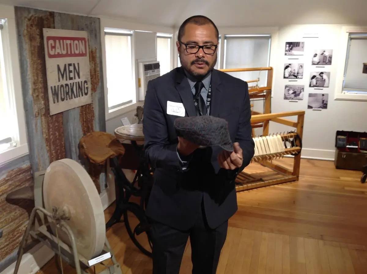 Anthony Ortega, curator, holds a welder's cap in an exhibit in Patton State Hospital