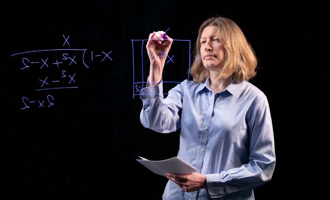 woman doing math on glass board