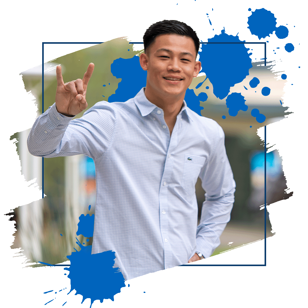 Student smiling while holding up CSUSB hand sign