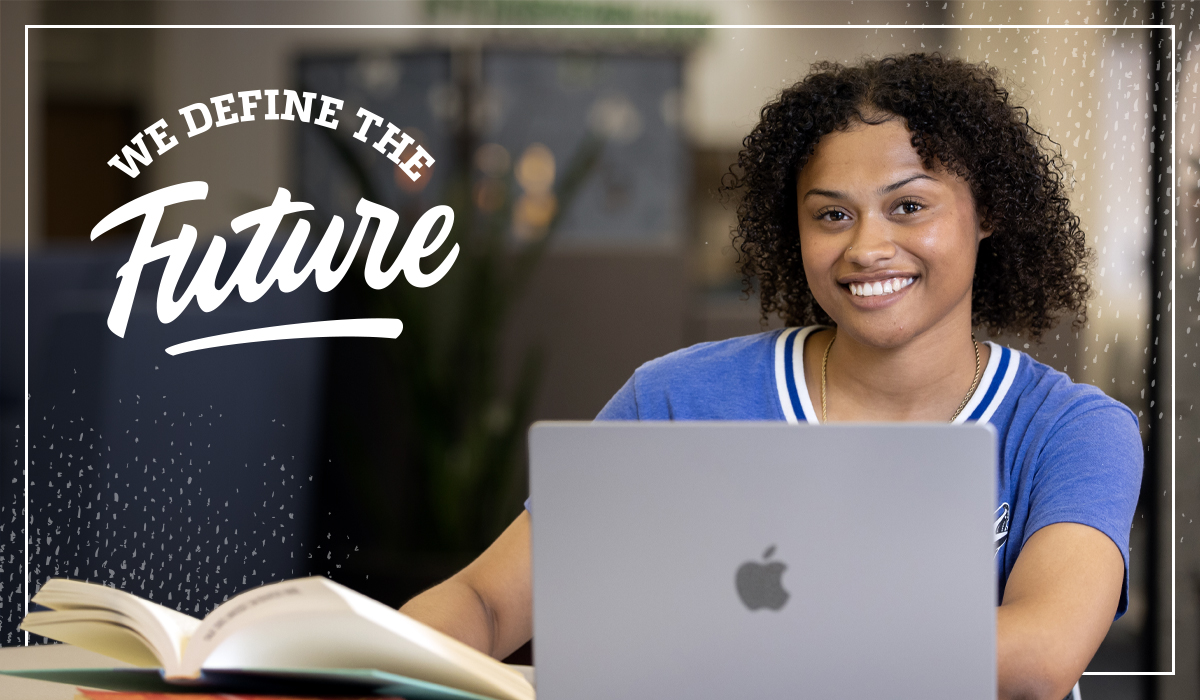 We Define the Future. Student smiles with laptop.