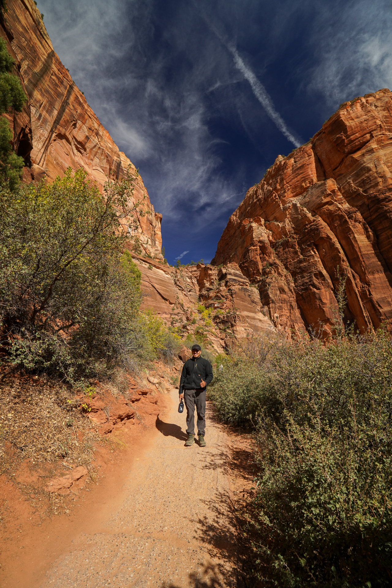 hiker on trail with red mountains