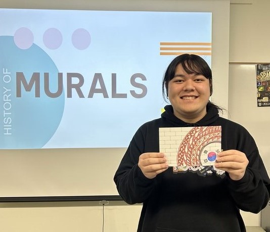 Student showing their miniature mural