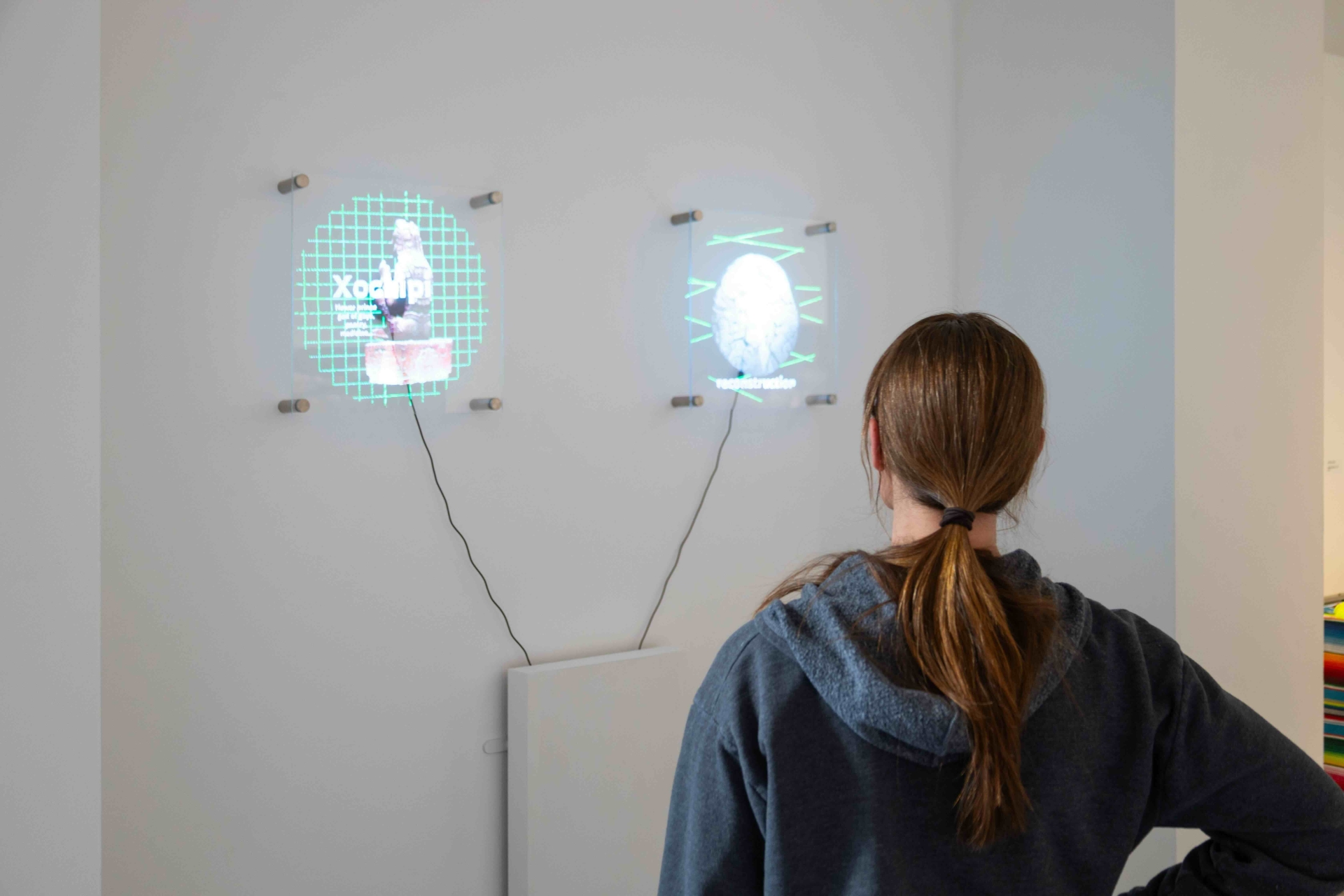 an individual looking at digital fans displaying an image from "Out of Sight Out of Need" exhibition