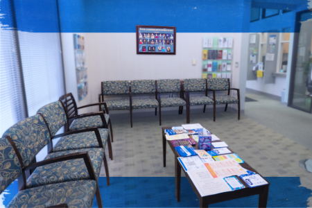 A waiting area showcasing chairs and tables in front of a blue wall, providing a welcoming space for visitors.