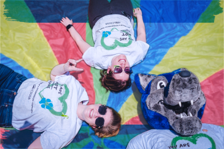 Three friends in matching t-shirts with a wolf mascot graphic, standing together and smiling at the camera.