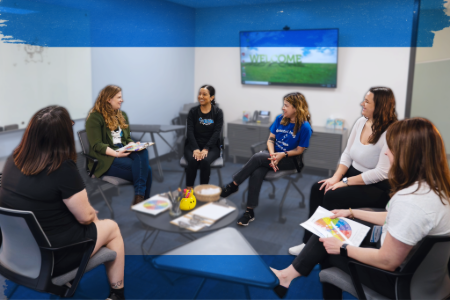  A group of diverse individuals engaged in discussion around in a circle in a modern group setting.