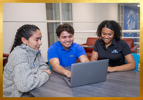 Three students looking at a computer