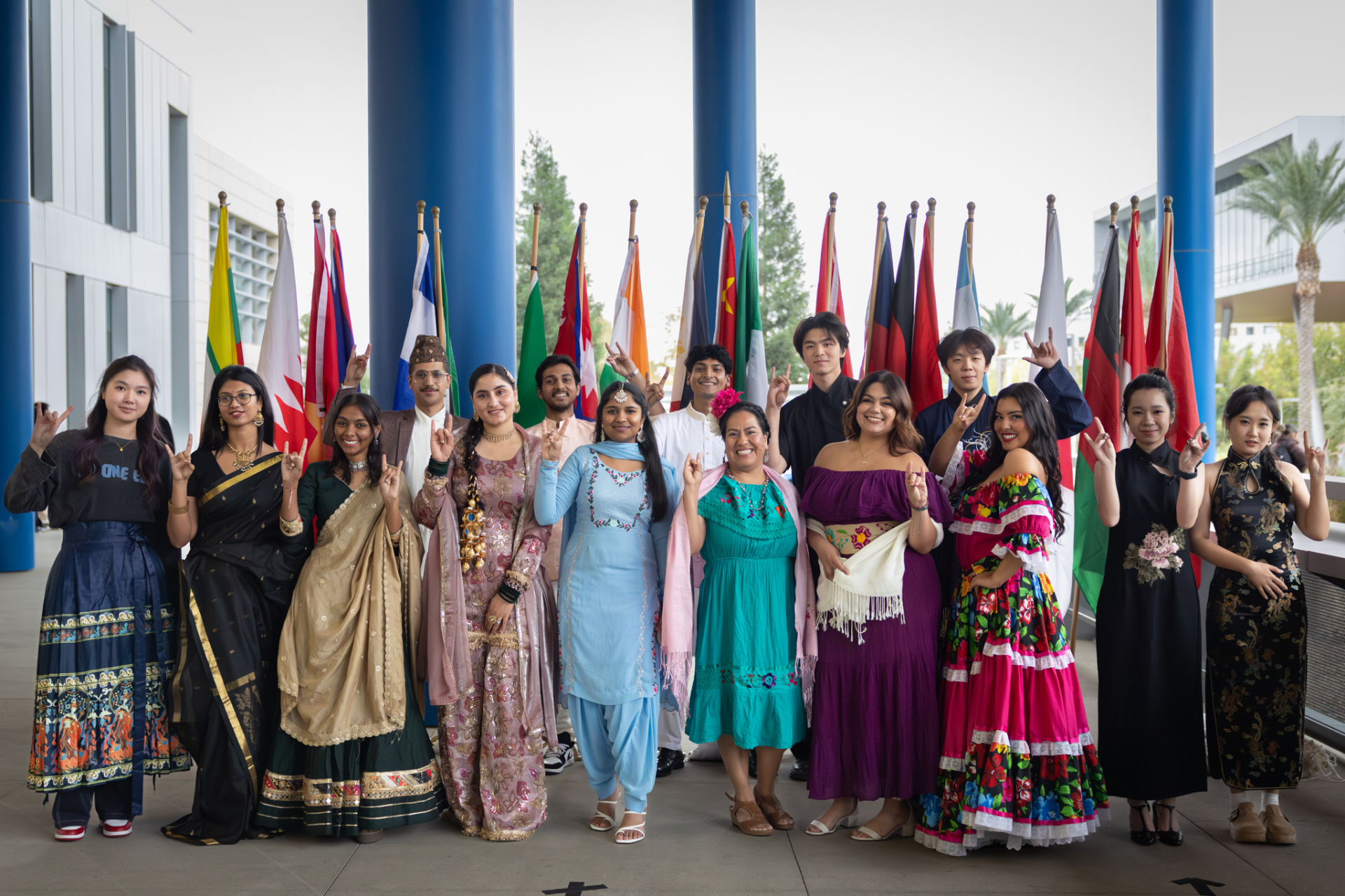 Students gather for a photo in front of international flags during the International Multicultural Fashion Show.