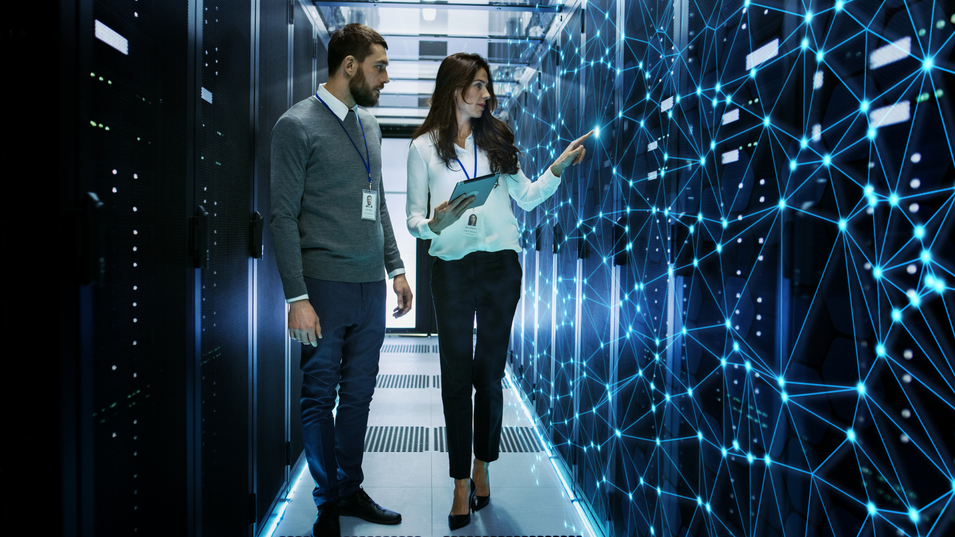 Two professionals analyzing an artificial intelligence network in a high-tech data center, illustrating machine learning, deep learning, and AI-driven technologies.