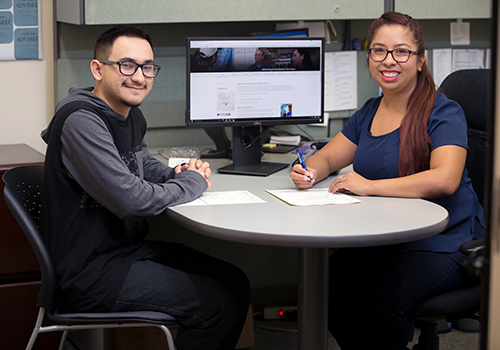 An advisor and student with pen and paper