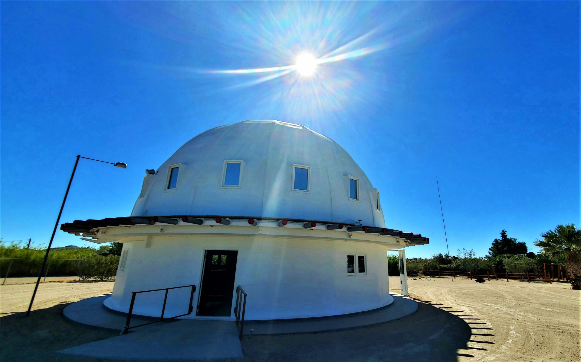 geodesic dome on desert with sun over