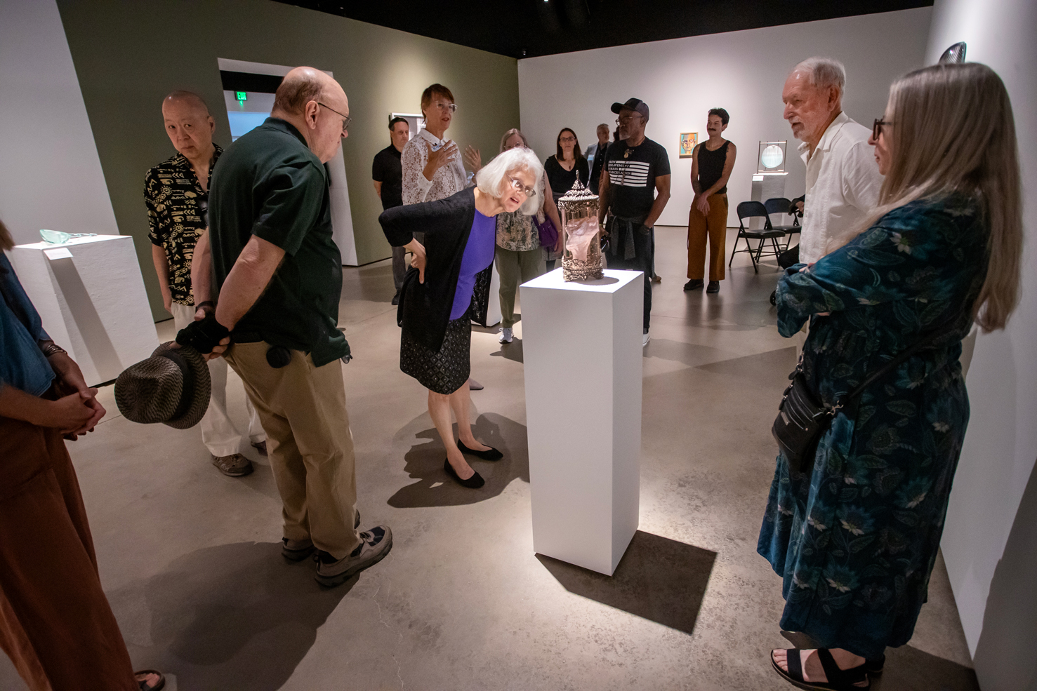 Renowned glass artist Katherine Gray (at back in white lace top) presents her artwork to visitors.