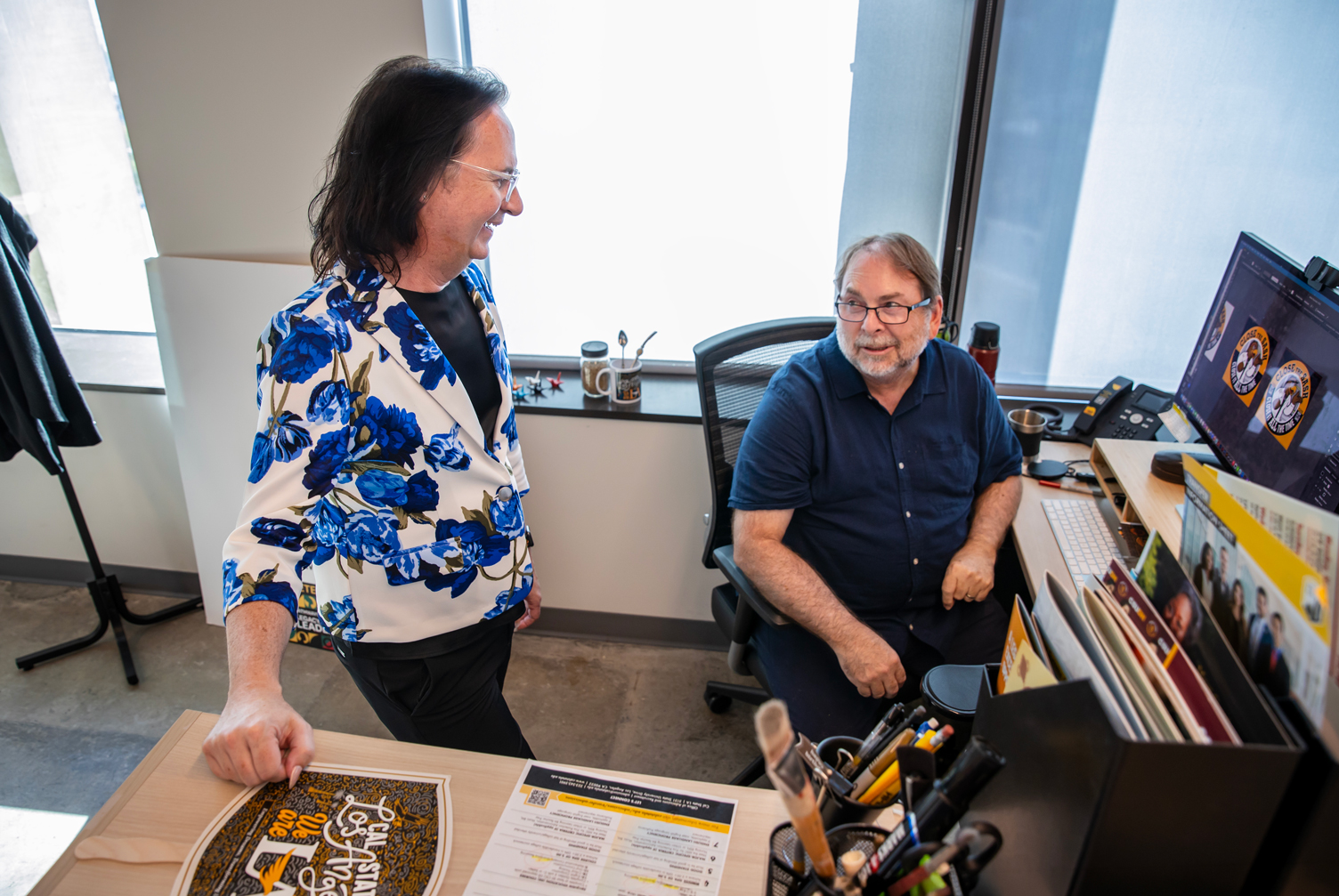 Hollins discussing a project with a graphic designer in the strategic communications office at Cal State LA.