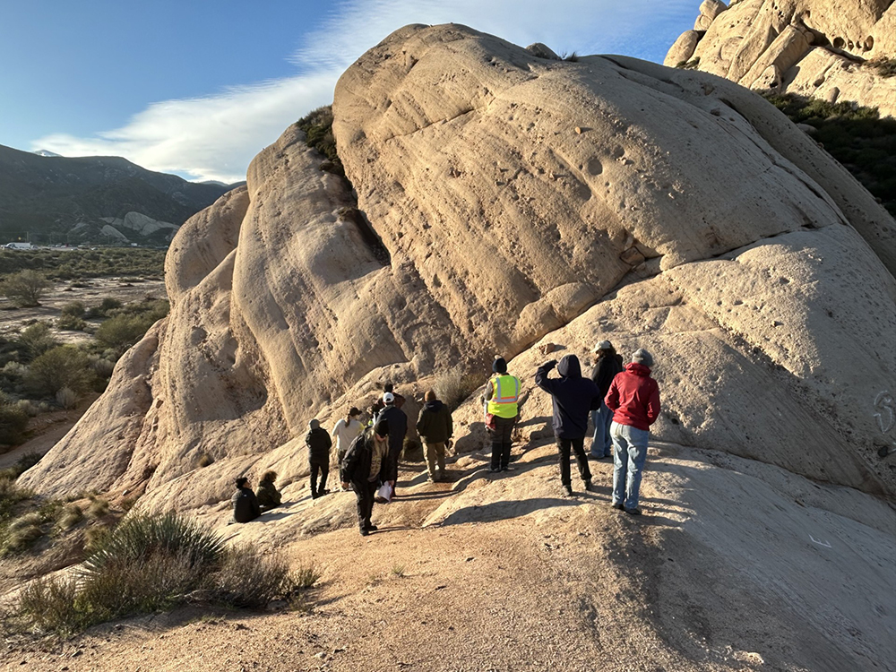 The Project DE-STESS participants examine an outcrop of the Cajon Valley Formation at Mormon Rocks in Phelan.