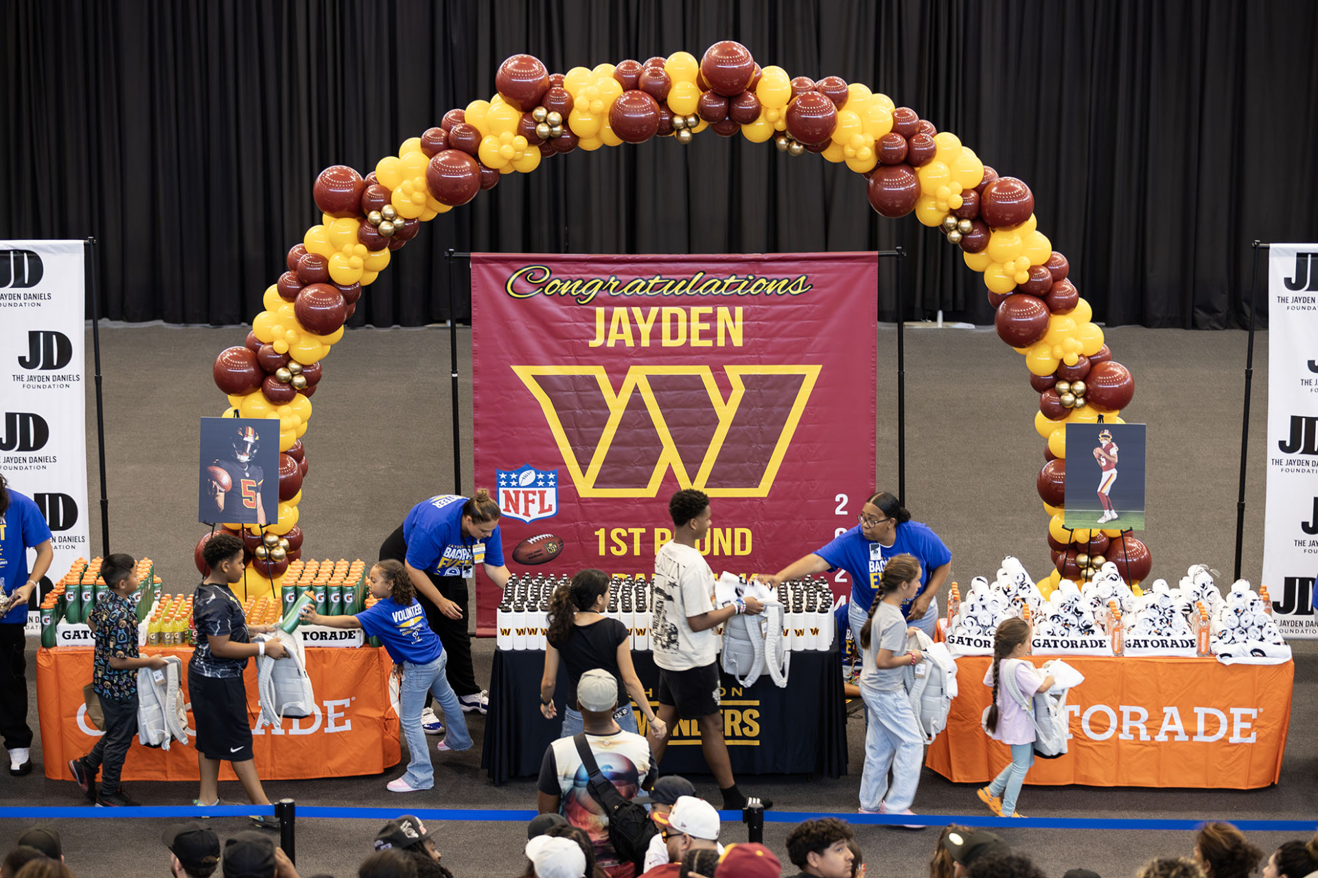 A line of children fill backpacks with school supplies and other items during the Jayden Daniels Foundation's Community Day at CSUSB.
