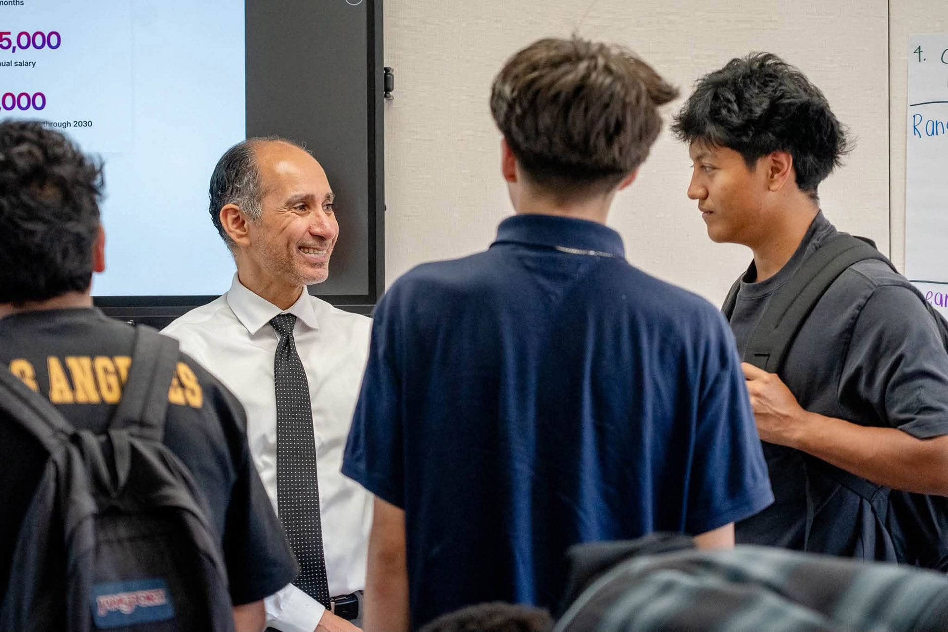 Nabeel Alzahrani, smiling, with three people, 2 with backs to the camera, the third facing Nabeel from the right.
