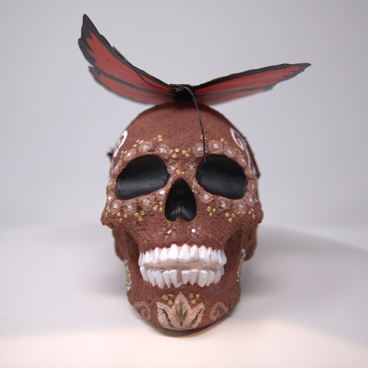 Brown calavera with a butterfly on top. 