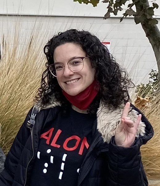 Medium length curly brown hair, glasses, black shirt