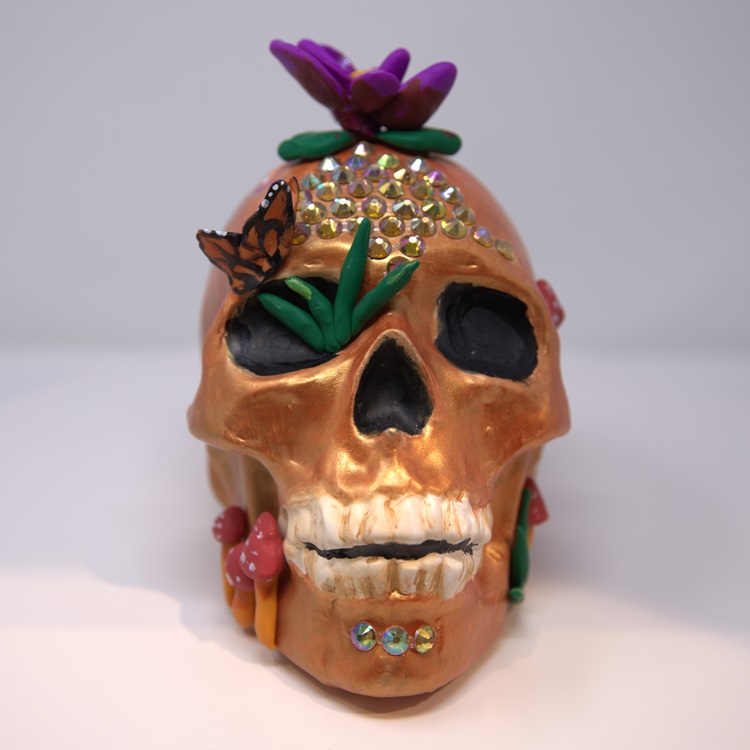 Bronze calavera with flowers and golden details, gemstones and a butterfly