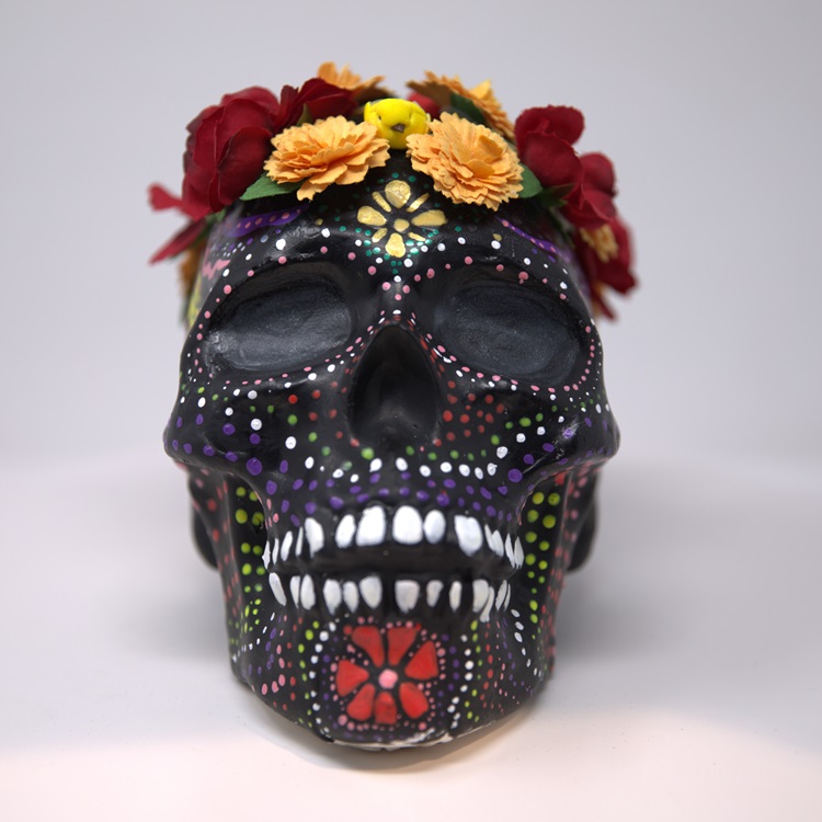 Black painted skull with colorful detail dots and a flower crow.