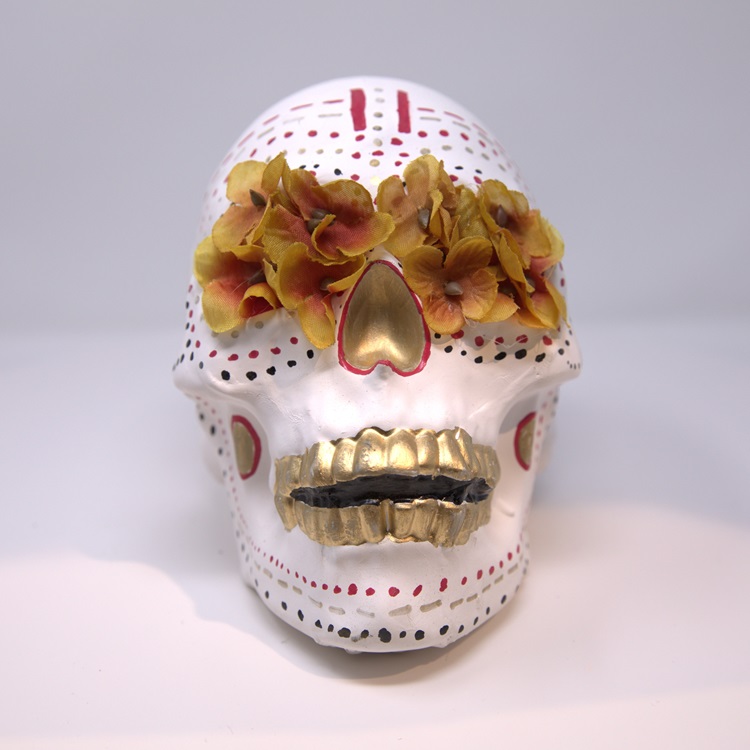 White skull with red black and gold details, and flowers for eyes.