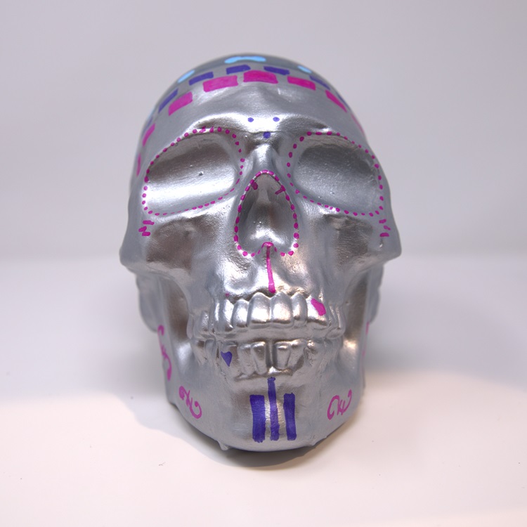 Silver painted skull with magenta, purple and blue details.