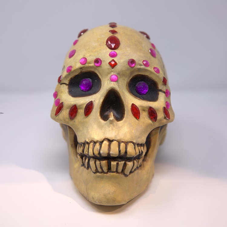 Beige and brown painted skull with red, pink and purple gemstones.