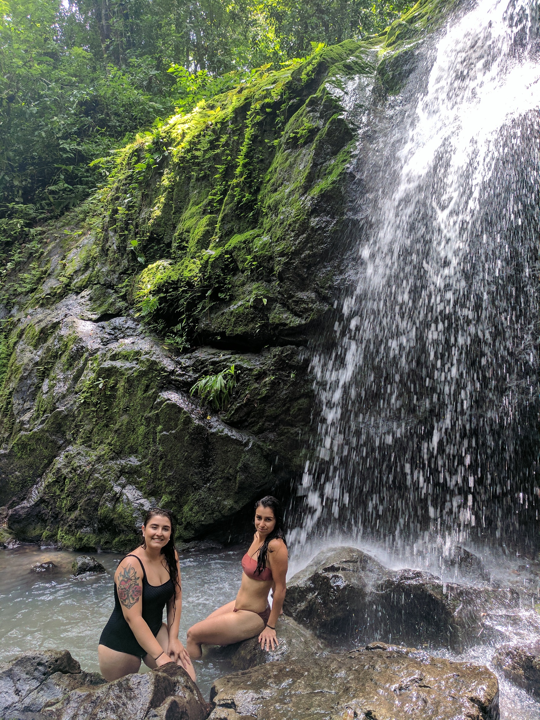 Two students sitting on rocks by waterfall in Costa Rica