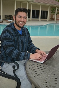 student on laptop by pool using internet 
