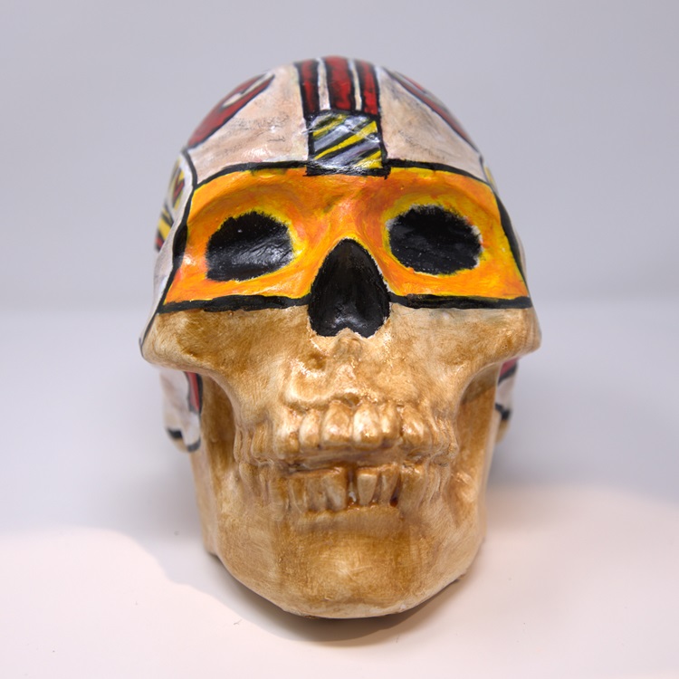 Beige skull with orange mask; red, black, and gray details. 