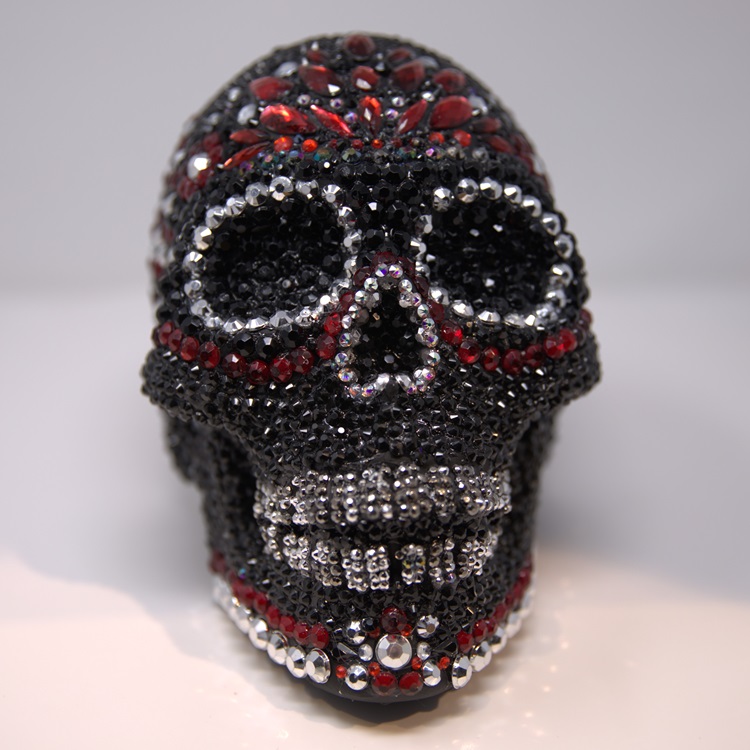 Black calavera adorned with black, red, and silver gemstones. 